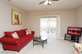 A living room with a red couch and a painting of an owl on the wall.